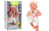 Baby doll in white and pink clothes, hat, pacifier, and blanket